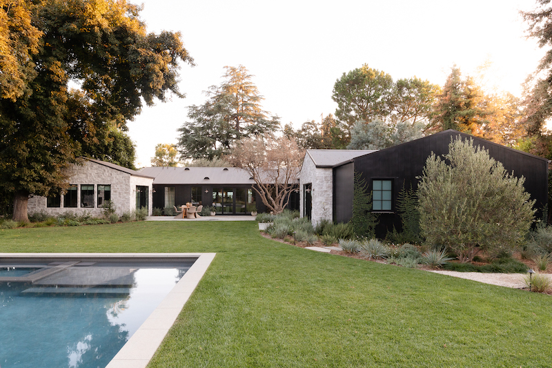 Backyard view of a Belgian farmhouse-style home, featuring Marvin Signature Ultimate windows and doors.
