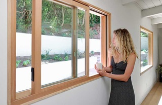 Woman holding coffee mug beside Marvin Ultimate Glider window.