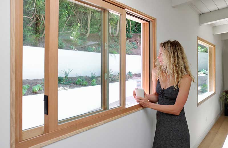 Woman holding coffee mug beside Marvin Ultimate Glider window.