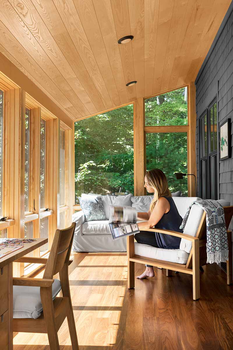 A woman reading a magazine on a porch featuring Marvin casement and direct glaze windows.