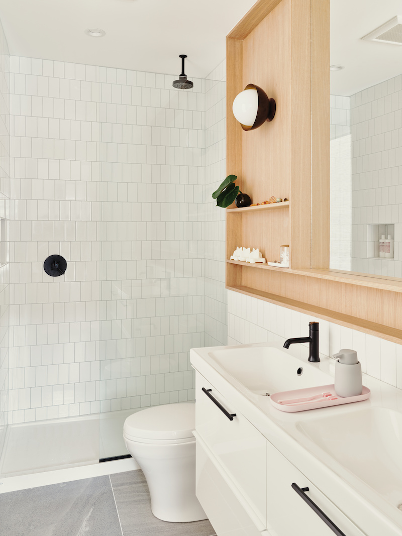 Main bathroom in a railroad style home with white tile and white oak cabinets 