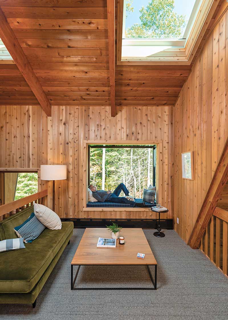 A man lying in the Marvin Skycove in the loft of The Minne Stuga cabin, with Marvin Awaken Skylights above.