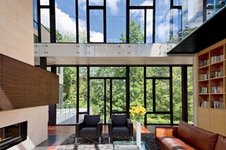 A photo of a living room with a fireplace, wall of books and floor-to-ceiling Marvin windows.