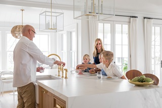 A family in their bright, white modern kitchen, featuring Marvin windows and doors.