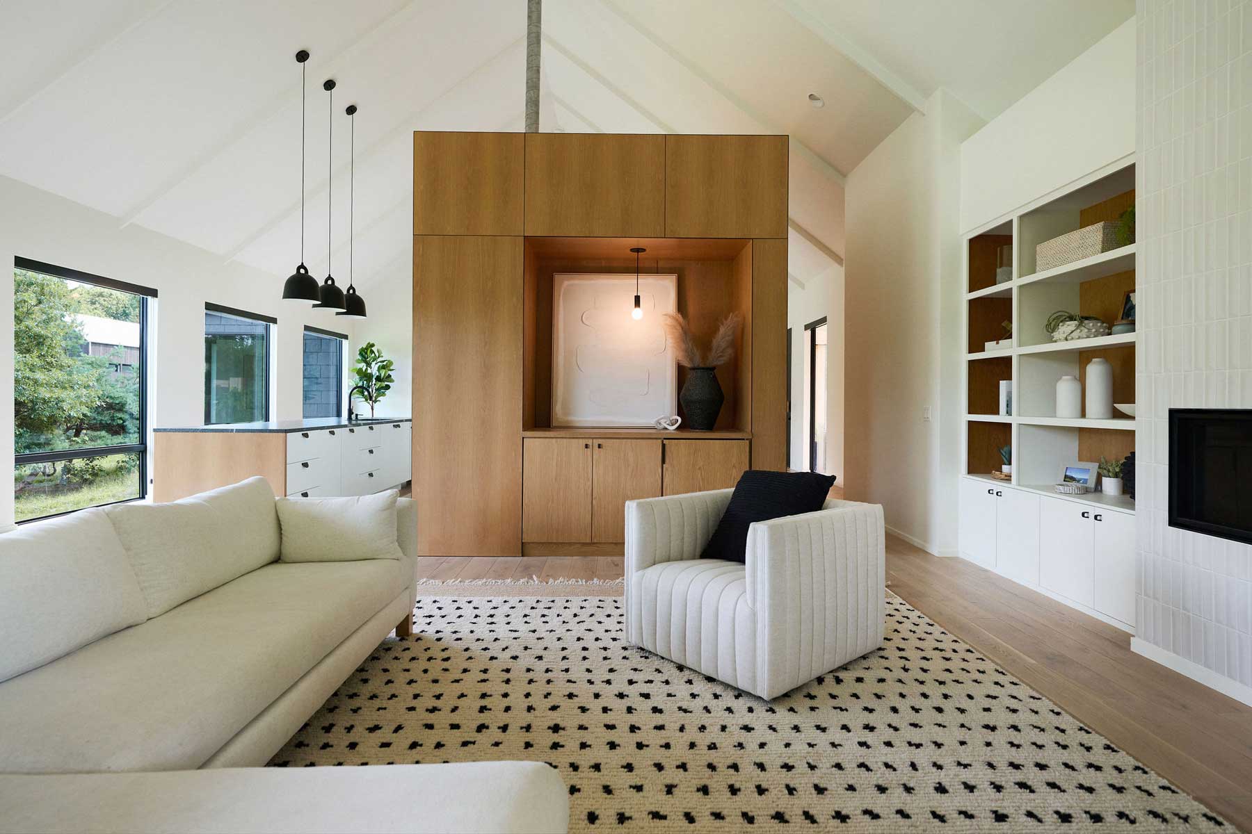 A modern, open-concept living room and kitchen with a white oak cube for storage space and Marvin Essential Direct Glaze windows.