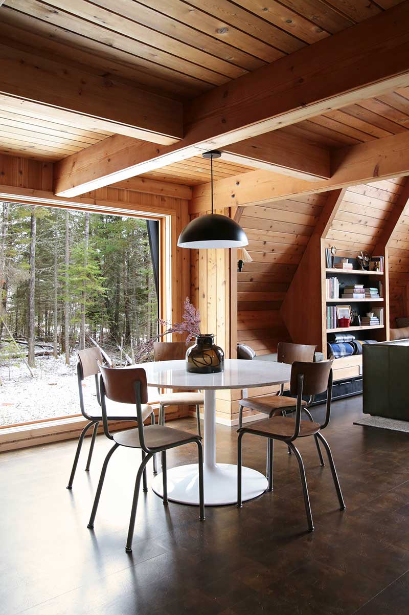 The dining room in The Minne Stuga with a table and four chairs beneath a pendant light next to a Marvin Ultimate Picture window.