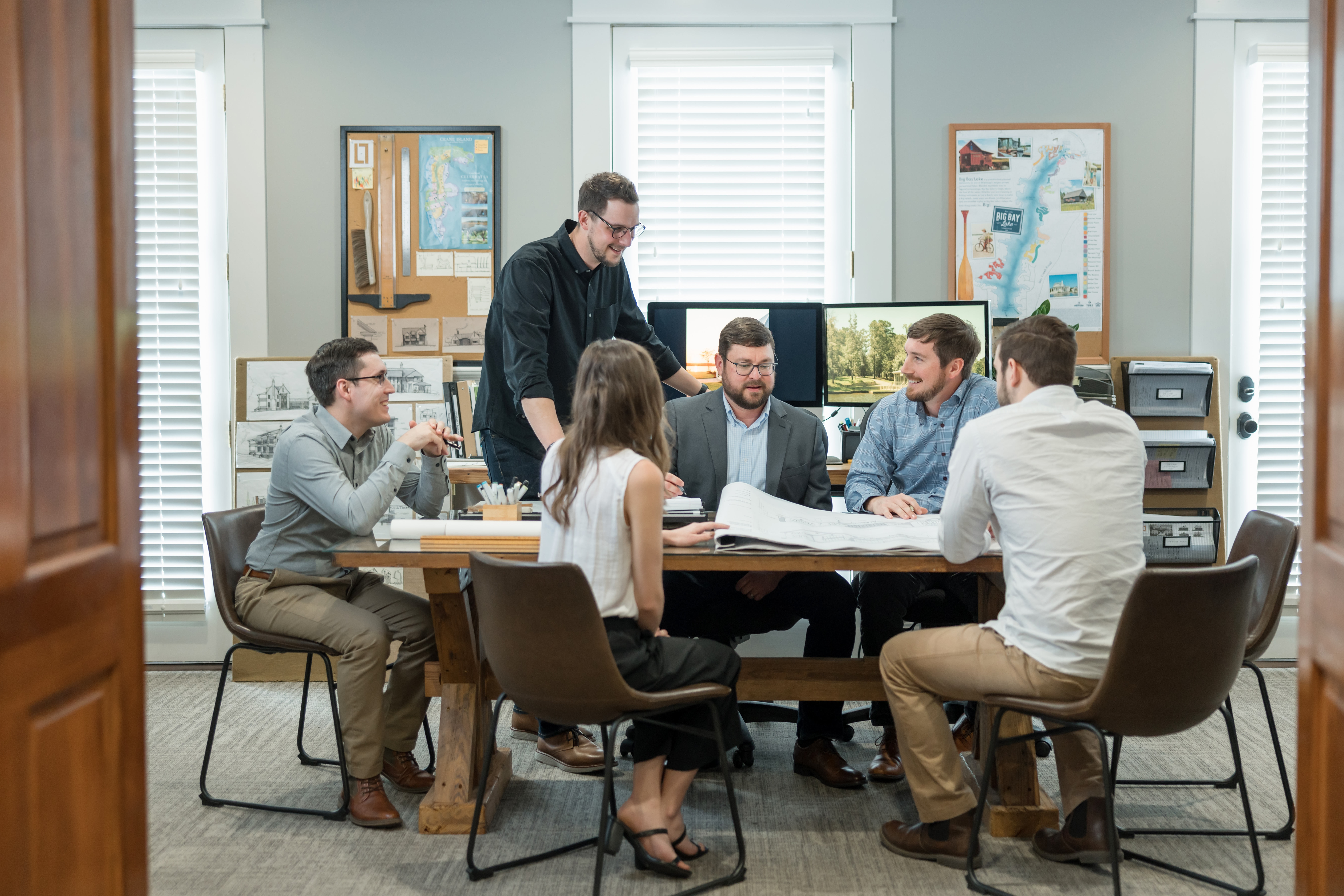 The team at Lake + Land studio in their office at a meeting table.