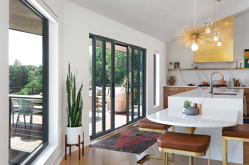 A sunny patio view showing Marvin Essential Casement Picture windows and Elevate Sliding Patio door.