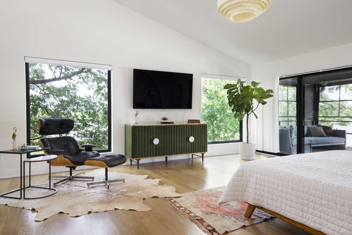 A mid-centuring modern living room featuring two Marvin Essential Casment Picture windows, TV, and lounge chair.
