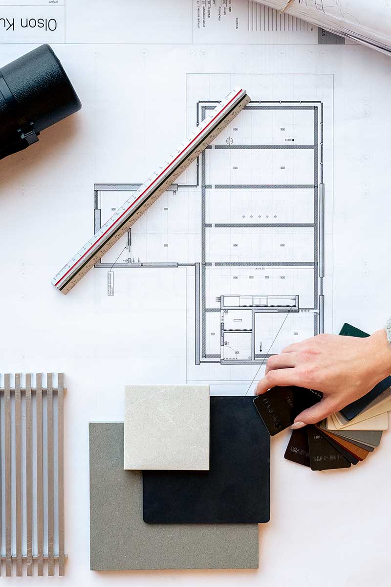 A mood board with house plans, paint chips, tiles, and a ruler.