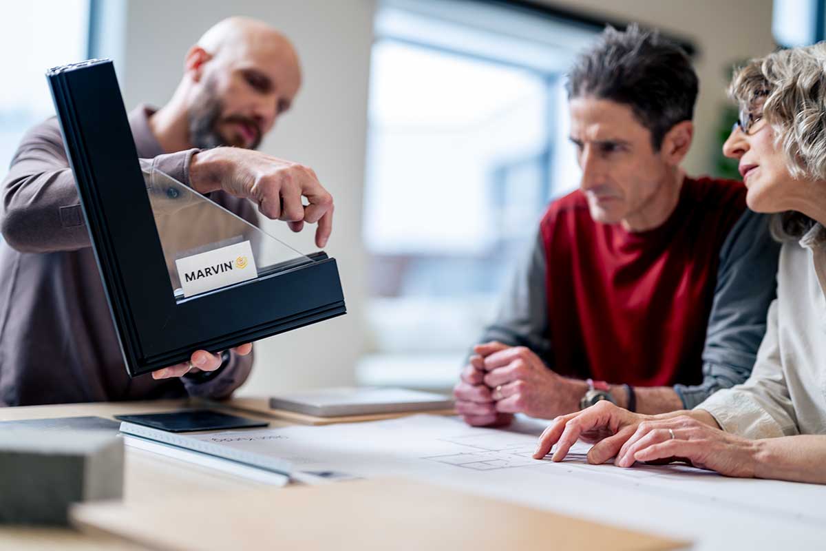 A man showing a couple a Marvin window corner sample.