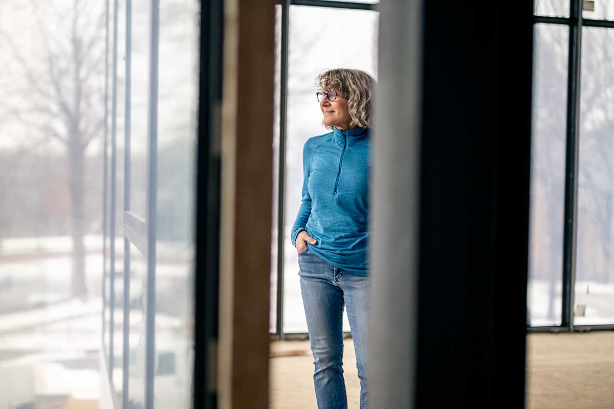 A woman with glasses looking through a Marvin Modern window.