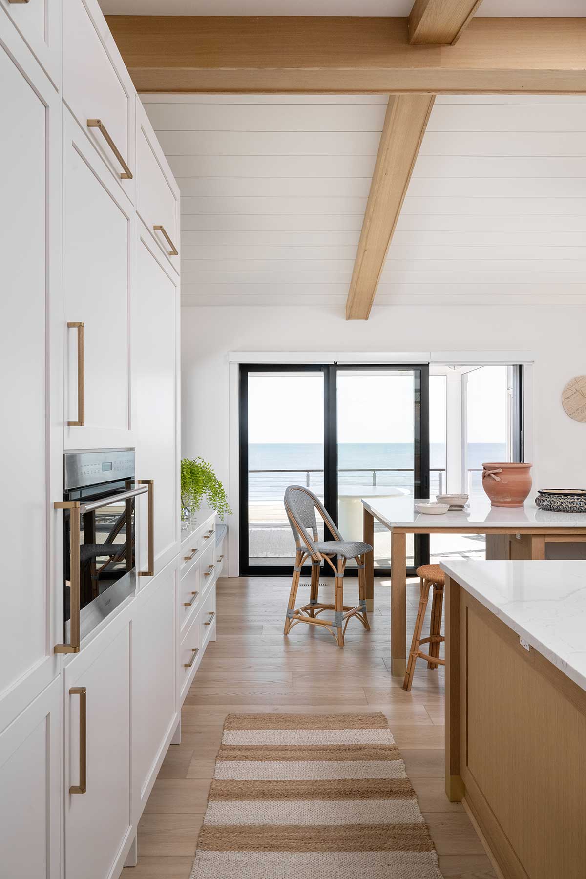 The kitchen of a home in Bethany Beach, Delaware, featuring a Marvin Modern Multi-Slide door and white cabinetry.