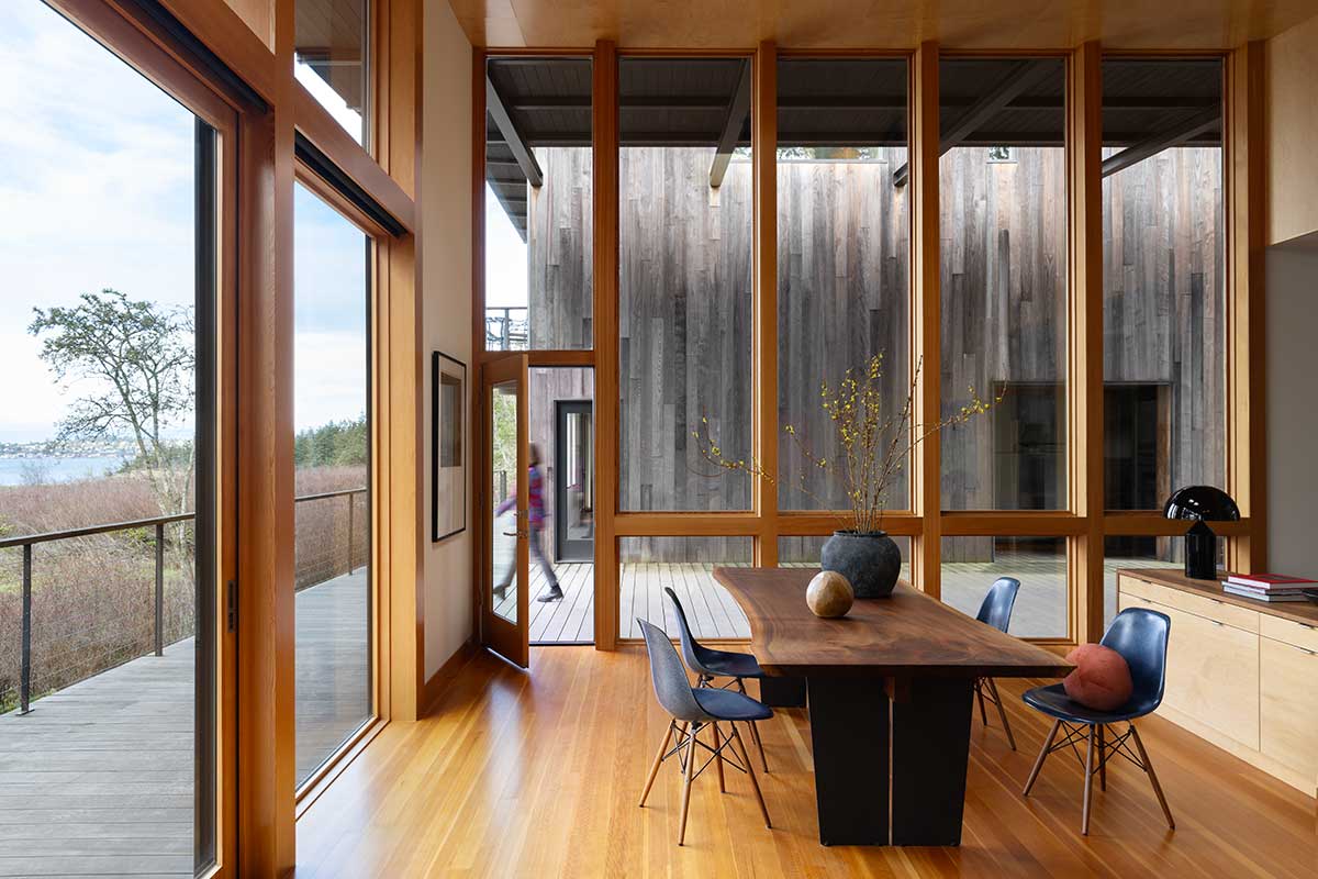 A living room in a modern home, featuring Marvin Ultimate Direct Glaze windows and a Marvin Ultimate Multi-Slide door overlooking a body of water.