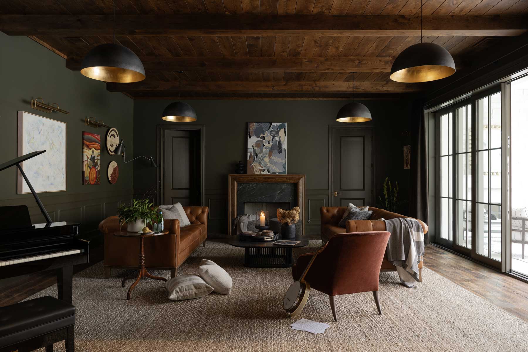 The lower level of the Southern Living Idea House 2023 in Leiper's Fork, TN, featuring dark green walls, a grand piano and a Marvin Ultimate Multi-Slide door.