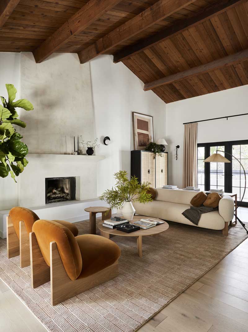 A modern living room in the Bobby Berk Firm’s office, featuring Marvin Ultimate Inswing French doors, a white stone fireplace and modern furnishings.
