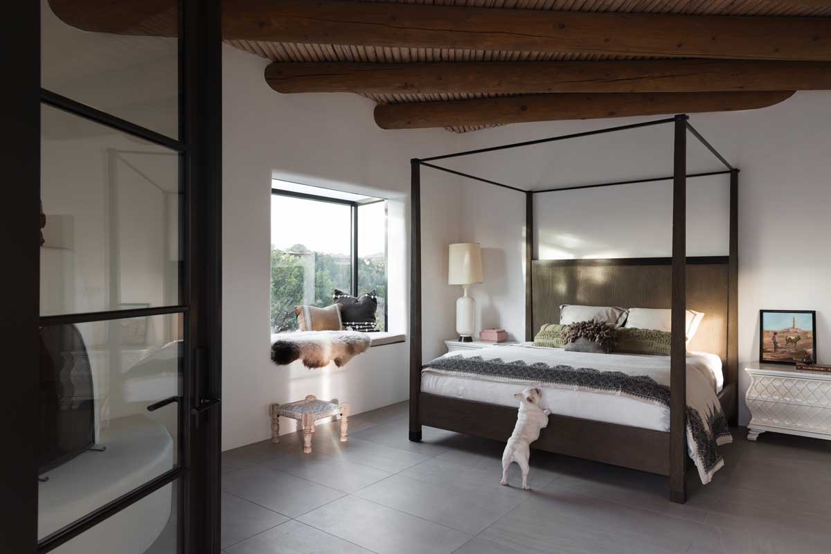 A French bulldog in the bedroom of an Adobe-style home in Santa Fe, New Mexico, featuring a Marvin Skycove and Marvin Ultimate Inswing French door.