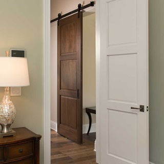 A dark brown TruStile raised panel barn door in a bedroom.