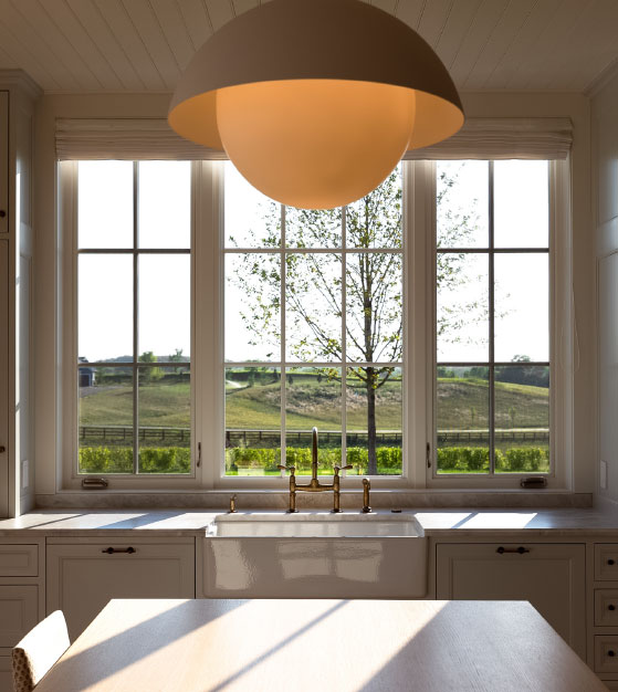 The kitchen inside a Swedish traditional home in Medina, Minnesota, featuring Marvin Ultimate Casement Narrow Frame windows above a farmhouse sink.