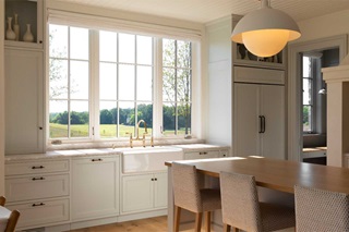 The kitchen inside a Swedish traditional home in Medina, Minnesota, featuring Marvin Ultimate Casement Narrow Frame windows above a farmhouse sink.
