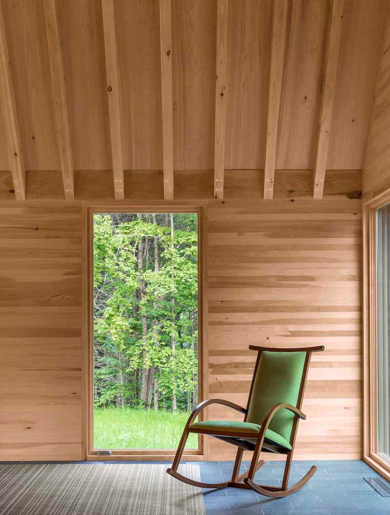 An interior photo of the Marlboro Music Cottages, featuring a Marvin Ultimate Casement window beside a rocking chair.