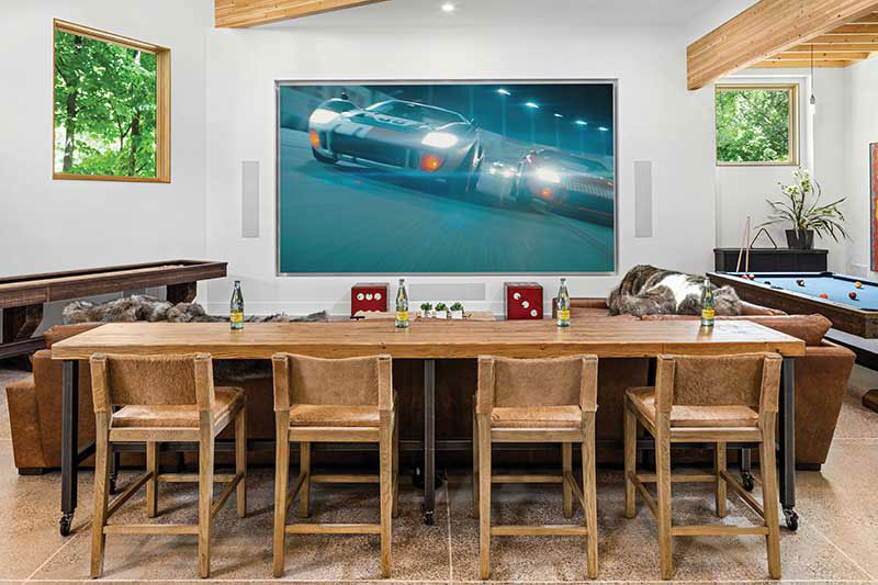 An entertainment center with a big-screen TV and pool table includes Marvin Ultimate Picture windows strategically installed to make the best use of natural light.