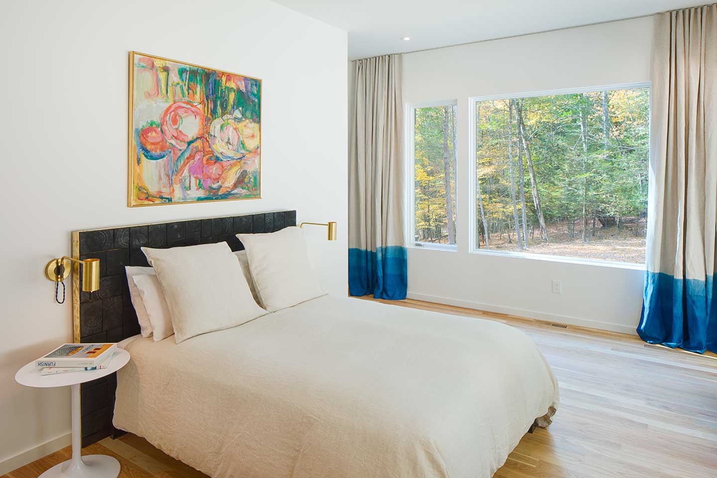 A contemporary bedroom featuring Marvin Ultimate Picture and Direct Glaze windows, with hand dyed indigo curtains.