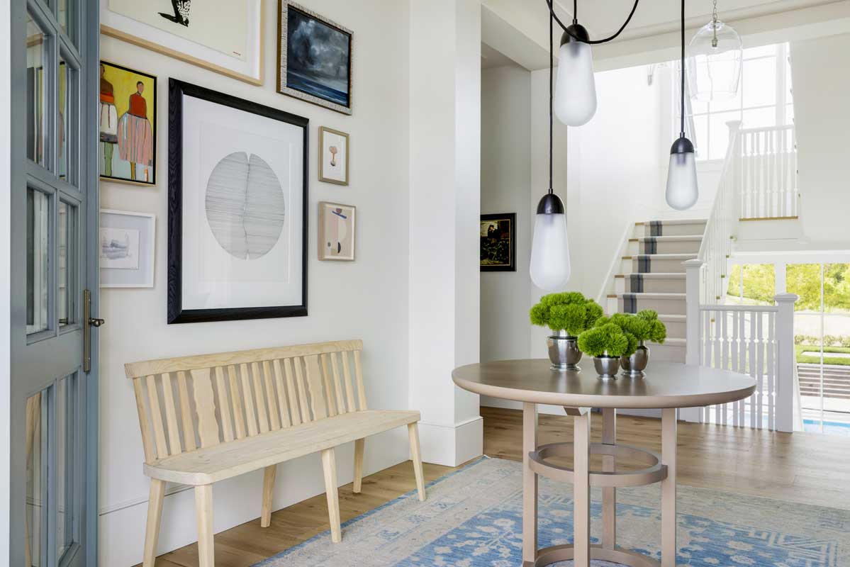 An entryway with a bench, table and wall decor