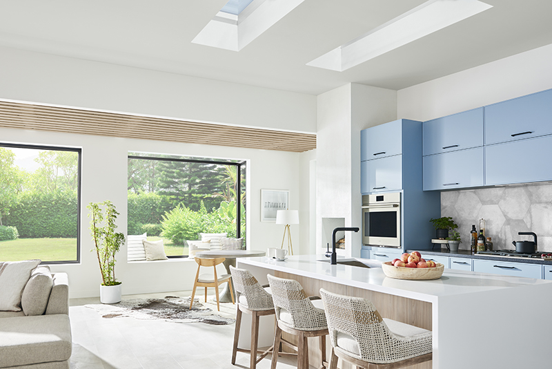 A man and woman in their kitchen, looking up at two Marvin Awaken Skylights with two Marvin Skycoves in the background.
