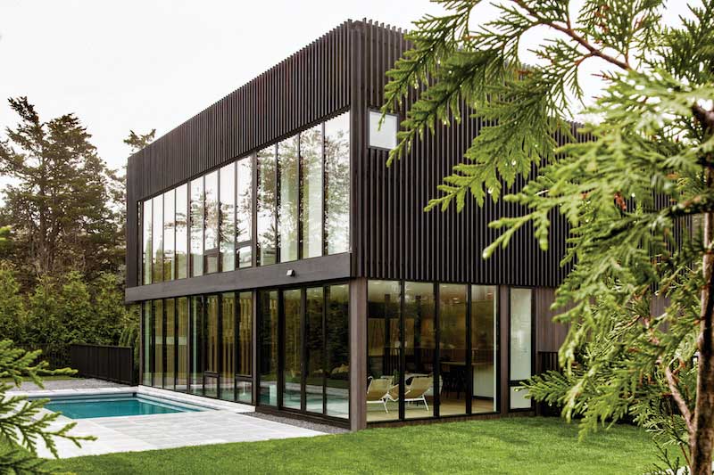 Exterior of a modern home in Sag Harbor, New York, with Marvin Modern awning, direct glaze, and casement windows and a pool. 