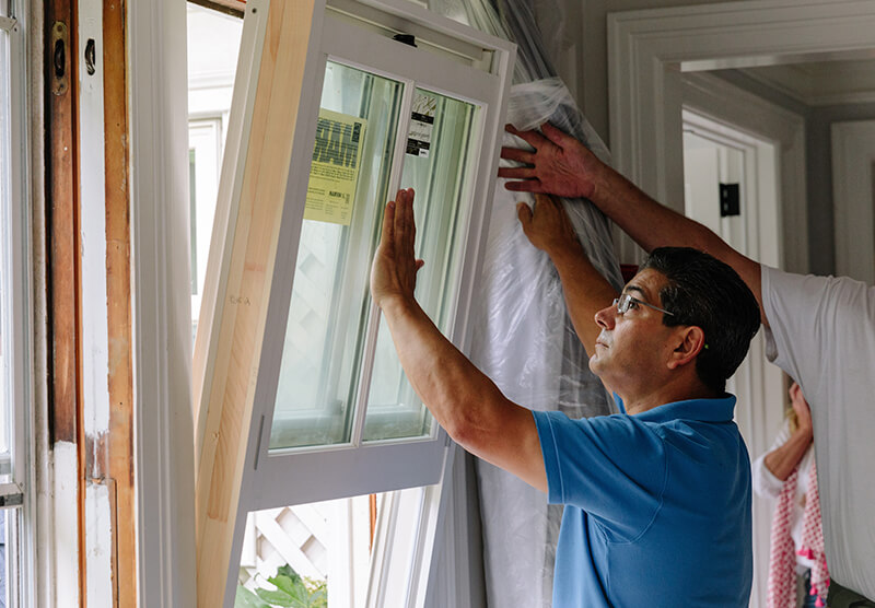 Window installer placing replacement windows and doors.